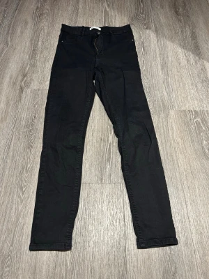 Svarta Molly skinny jeans strl. L - Svarta Molly skinny jeans från Gina Tricot med smal passform och dragkedja. Byxorna har hög midja och är tillverkade i ett stretchigt bomullsmaterial för en bekväm känsla. Perfekta för dig som gillar en tight och stilren look. Inte mycket använda.