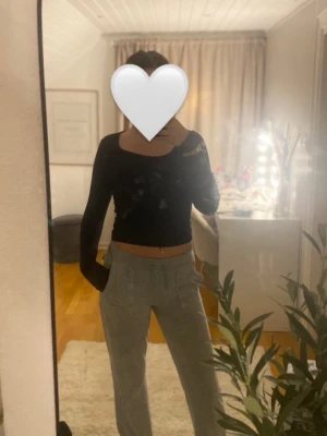 Grå mjukisbyxor med snörning - Säljer ett par grå mjukisbyxor med snörning i midjan tappat båda metal klämmor och stora fickor fram. Baktill finns två fickor med lock och knapp. Byxorna har en loose passform och är perfekta för chill dagar. Materialet är mjukt och skönt, troligtvis bomull eller polyester.