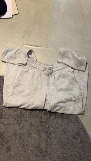 Ljusgrå mjukisbyxor XS - Superbekväma ljusgrå mjukisbyxor med resår och snörning i midjan. Byxorna har två fickor fram och två bak, perfekta för chill eller träning. Mjukt material som känns skönt mot huden.
