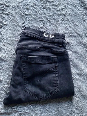 Mörkgrå dondup jeans storlek 33 - Snygga mörkgrå jeans från dondup. Jeansen har en enkel look utan slitningar och är tillverkade i stretchigt denimtyg för extra komfort. Perfekta för dig som gillar en stilren och modern vibe.