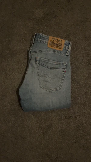 Replay ljusblå jeans regular boot - Säljer ett par ljusblå jeans från Replay med klassisk femficksdesign och snygga slitningar. Modellen har en utsvängd passform och normal midja, med Replay-lapp bak i midjan. Jeansen är tillverkade i mjukt denim och har dragkedja och knapp framtill.