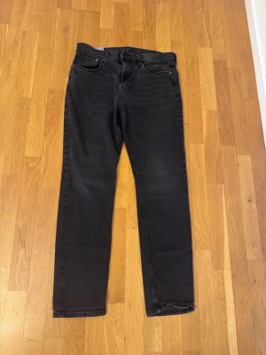 Svarta slim fit jeans från H&M - Storlek 32/32. Svarta slim fit jeans från H&M med klassisk femficksdesign och dragkedja i gylfen. Jeansen har en rak siluett med smal passform och är tillverkade i mjukt denimtyg. Perfekt för dig som gillar en stilren look med lite edge. Knappt använda
