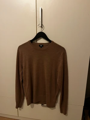 Beige merinoulltröja från Uniqlo - Säljer en stilren beige tröja från Uniqlo i mjuk merinoull. Tröjan har rund halsringning, ribbade muddar och lång ärm. Perfekt för lager-på-lager och funkar året runt. Enkel och clean design som passar till allt.