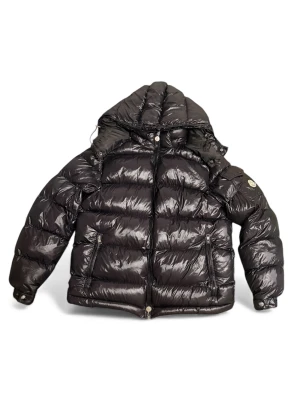 Svart Moncler pufferjacka med huva - Snygg svart pufferjacka från Moncler med glansig finish och stor huva. Jackan har två dragkedjefickor framtill, Moncler-logga på ärmen och quiltad design. Fylld med vitt gåsdun för extra värme. Perfekt för kalla dagar och riktigt stilren look.
