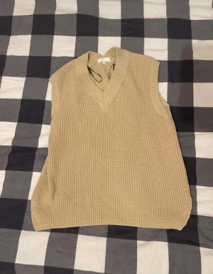 Beige stickad väst  - Beige stickad väst från H&M i storlek S. Västen har en v-ringning och är perfekt att styla över en skjorta eller t-shirt! 
