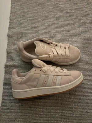 Beige Adidas Campus sneakers i mocka - Säljer ett par snygga Adidas Campus sneakers i ljusrosa, bilderna gör inte färgen rättvis så skriv privat om ni vill ha mer bilder. Endast använda två gånger, storlek 39 och 1/3