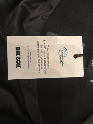 Svart kappa med bälte från Bik Bok - Stilren svart kappa från Bik Bok i storlek S. Jackan har ett snyggt bälte i midjan, knappar framtill och är tillverkad av återvunnen polyester och ull. Långärmad och med slät insida, perfekt för dig som gillar minimalistisk look. Aldrig använt den, och den är i väldigt bra skick 