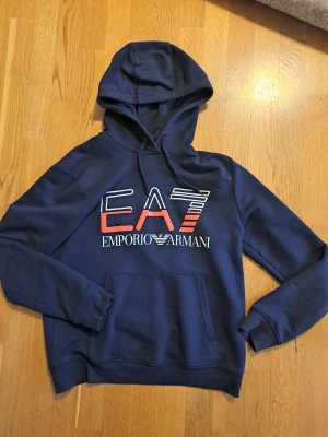 EA7 Emporio Armani hoodie - Säljer en EA7 Emporio Armani hoodie som är i mycket bra skick. Hoodien är i nyttskick och har inga skador eller liknande. Köpt för 1350kr.