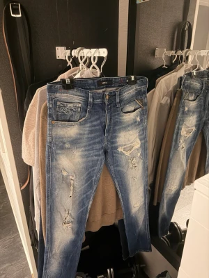Replay ” anbass ” jeans - Säljer ett par blå jeans från Replay ” Anbass ” med slitna detaljer och snyggt tvättad look. Jeansen har klassisk femficksdesign, dragkedjegylf och Replay-logga på fickan. Perfekt för dig som gillar en avslappnad och trendig stil.