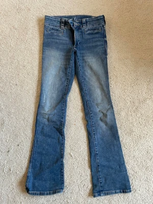 Low waist bootcut jeans med fickor - Ett par mörkblåa jeans som är bootcut, lowwaist och är använda ett fåtal gånger. Fickor med lock på baksidan som är en jättefin detalj. Skriv gärna till mig om ni vill ha fler bilder!