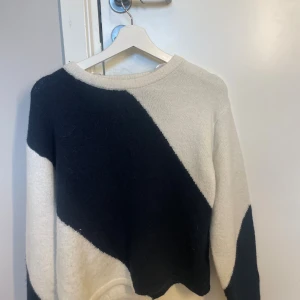 Svartvit stickad tröja Gina Tricot - Snygg stickad tröja från Gina Tricot i storlek 158/164. Tröjan har ett coolt diagonalt mönster i svart och vitt, rund halsringning och långa ärmar. Perfekt för att lyfta din höst- eller vinterstil.