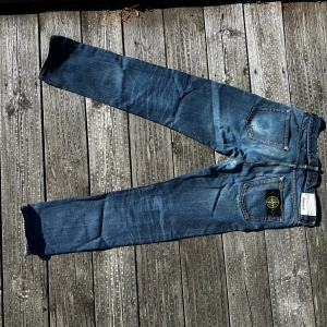 Blå jeans från Stone Island - Säljer ett par blå jeans från Stone Island med klassisk patch på bakfickan. Jeansen har raka ben, normal passform och snygga slitningar för en cool look.  Storlek w30 L30 i använt sick