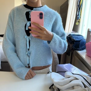 Ljusblå stickad kofta med rosetter - Superfin ljusblå stickad kofta med långa ärmar och fyra söta rosetter framtill istället för knappar💕priss kan diskuteras men inte under 150 kr