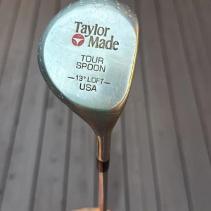 TaylorMade Tour Spoon 13° Loft - TaylorMade Tour Spoon golfklubba med 13° loft, tillverkad i USA. Klassisk modell med tydliga tecken på användning och normalt slitage på klubbhuvudet, men i gott skick för fortsatt spel. Perfekt för samlare eller golfare som söker en ikonisk fairwaywood.