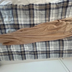 Beiga mjukisbyxor från Juicy Couture - Supermjuka beiga mjukisbyxor från Juicy Couture med klassisk JC-logga broderad på benet och silverfärgad knappdetalj. Byxorna har en relaxed passform och är tillverkade i ett lent fleecematerial som känns riktigt skönt mot huden.