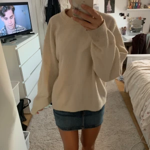 Beige stickad oversized tröja - Mysig beige stickad tröja med oversized passform och långa ärmar. Tröjan har en enkel design med rund halsringning och ribbade muddar vid ärmslut och nederkant. Perfekt för lager-på-lager under kyliga dagar.