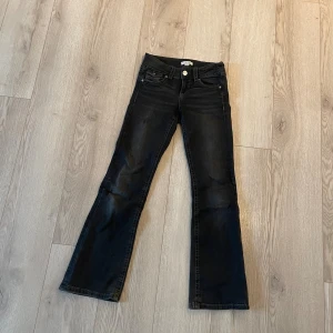 Svarta bootcut jeans Gina Tricot 152 - Svarta jeans från Gina Tricot i storlek 152. Modellen har bootcut-ben, klassiska fem fickor och snygga detaljer med knappar på bakfickorna. Jeansen är i stretchigt denimtyg och har en mörk tvätt som passar till allt.