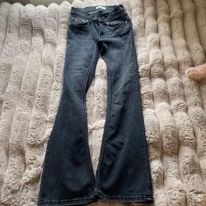Svarta bootcut jeans med rå kant - Snygga svarta bootcut jeans med rå, fransad kant nertill. Klassisk femficksmodell med dragkedja och knapp. Jeansen har en mörk tvätt och är tillverkade i mjukt denimtyg som sitter skönt på kroppen.