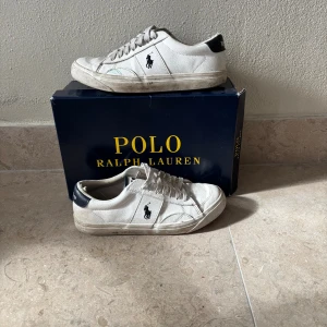 Vita sneakers från Polo Ralph Lauren - Snygga vita sneakers från Polo Ralph Lauren med klassisk låg profil och svart logga på sidan. Stl 37. Pre laced med loosed lace style. Perfekta för en clean och stilren look. Nypris 1300kr