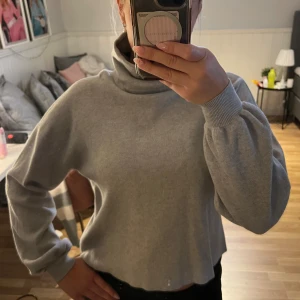 Grå polotröja från Vero Moda - Mysig grå polotröja från Vero Moda med lång ärm och breda muddar. Tröjan har en lös passform och hög polokrage, perfekt för kyliga dagar.💕