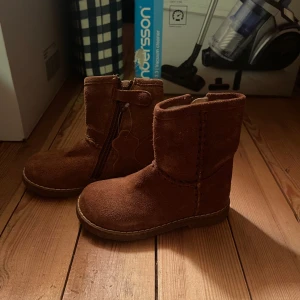 Bruna mockaboots från Excellent, stl 23 - Säljer ett par bruna boots i mocka från Excellent, storlek 23. Skorna har dragkedja på sidan och dekorativ söm längs skaftet. Perfekta för höst och vinter med sin mjuka insida och platta sula.