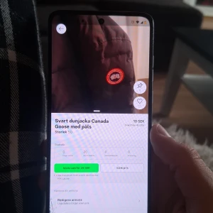 Svart dunjacka från Canada Goose - Säljer en svart dunjacka från Canada Goose med klassisk logga på bröstet. Jackan har en fyllig look och är perfekt för kalla dagar. Utrustad med huva och pälsdetalj, samt praktiska fickor och dragkedja framtill.