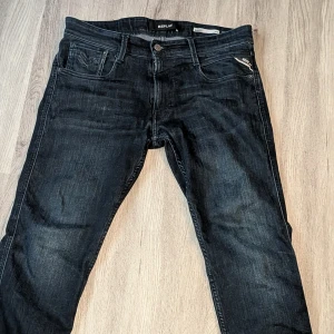 Replay Anbass Slim Fit Jeans Svart - Snygga svarta Replay Anbass jeans i slim fit med klassisk femficksdesign och diskreta slitningar. Jeansen har dragkedjegylf, läderpatch bak och är tillverkade i stretchig bomullsdenim för en bekväm passform.