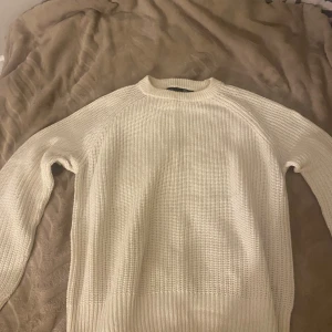 Vit stickad tröja från 157 - Säljer en vit stickad tröja från 157 i storlek S. Tröjan har en klassisk rund halsringning och är ribbstickad med långärmade ärmar. Perfekt för lager-på-lager och enkel att matcha med jeans eller kjol.