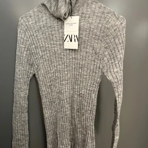 Grå ribbad polotröja från Zara - Snygg grå ribbstickad polotröja från Zara i alpacka- och ullblandning. Tröjan har lång ärm, tight passform och hög polokrage. Perfekt för lager-på-lager och en clean look. Supermjuk och stilren, passar till allt.