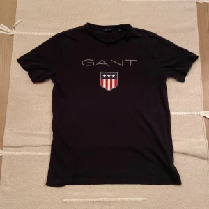 Svart GANT t-shirt - Svart t-shirt från Gant. T-shirten har rund hals och korta ärmar, tillverkad i mjuk bomull. Riktigt bra passform!