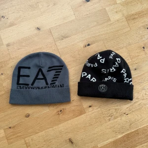 EA7 och Paris mössor - Två snygga mössor: en grå EA7 Emporio Armani med svart logga och ribbad kant, samt en svart Paris-mössa med vit text och rund Paris-emblem framtill. Perfekt för dig som gillar streetstyle och vill ha något som sticker ut. 150 kr per mössa
