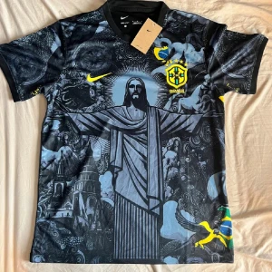 Nike Brasil fotbollströja svart/gul - Snygg Brasilien fotbollströja från Nike med unikt svart och grått mönster, stora tryck av Kristusstatyn och brasilianska symboler. Gula detaljer, CBF-emblem och Nike-logga. Tillverkad i Dri-FIT material som andas. Perfekt för dig som vill sticka ut på planen.