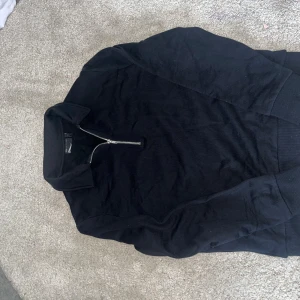 Svart half zip tröja från ASOS - Svart långärmad tröja från ASOS med krage och silverfärgad half zip-dragkedja framtill. Tröjan har en klassisk passform och är tillverkad i mjuk bomull, perfekt för lager-på-lager-stil. Enkel och stilren design som funkar till det mesta. Har inte allts använts. 