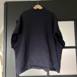 Mörkblå stickad tröja från Kappahl - Mörkblå stickad tröja från Kappahl i storlek M. Tröjan har en hög ribbad krage och korta ärmar med lös passform. Använd få gånger men det är en bleknings fläck längst ner på tröjan, syns inte så mycket🫶🏻