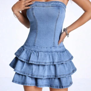 Blå jeansklänning med volanger - Supersöt jeansklänning i ljusblå denim med axelbandslös design och figurnära passform. Kjolen har flera lager volanger som ger en extra cool och lekfull vibe. Perfekt för dig som gillar att sticka ut och vill ha en trendig look. Klänningen är ärmlös och har en snygg, tight siluett. Köpte för 580 från en tjej på plick💞💞