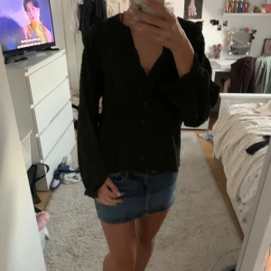 Mörk grön blus med volangdetaljer - Säljer en mörk grön långärmad blus med v-ringning och knappar framtill. Blusen har volangdetaljer längs axlar och ärmar som ger en trendig look. Materialet känns lätt och flowy, perfekt för dig som gillar en stilren men ändå cool vibe.  Xs/s