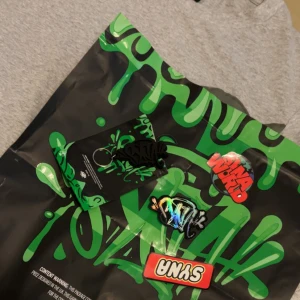 Short set från Syna World - Short set från Syna World med stort grafiskt tryck i mörkgrönt på framsidan. T-shirten är tillverkad i 100% bomull och har en klassisk, avslappnad passform med korta ärmar. Perfekt för dig som gillar streetwear och unika prints.