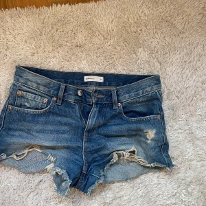 Blå jeansshorts från Gina Tricot storlek 32 - Säljer ett par blå jeansshorts från Gina Tricot, modell Perfect Jeans. Jätte snygga slitna kanter till. Storlek 32