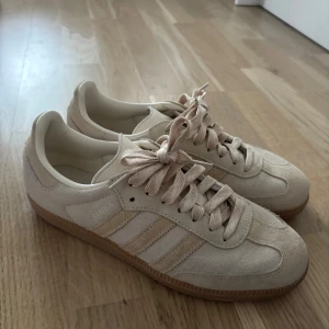  Adidas Samba sneakers mocka - Snygga Adidas Samba sneakers i beige. Skon har ovandel i mocka och textil, platt sula i gummi och snörning framtill. Använda max tre gånger men det finns tecken på användning!! Storlek 40, köpt för 1449 och säljer för 1000. Tillkommer ett till par snören. Pris kan diskuteras 