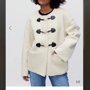 Beige teddyjacka med spännen från MQ - Säljer en beige teddyjacka från MQ med oversized passform. Jackan har tre svarta spännen framtill, stora fickor och breda ärmar. Perfekt för dig som gillar en chill och trendig look.