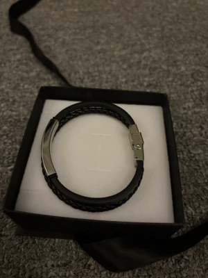 Svart silvrigt armband - Säljer detta snygga armband som passar till många outfits! Nypris är runt 800kr från ur och pen!