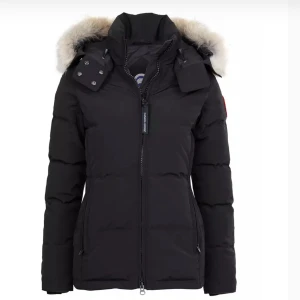 Canada Goose jacka  - Snygg svart dunjacka från Canada Goose med fluffig päls på huvan och dragkedja framtill. Jackan har en klassisk pufferstil, hög krage och praktiska fickor. Perfekt för kalla dagar när du vill hålla stilen och värmen. Knappt andvänd 