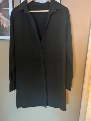 Svart långärmad skjorta - Enkel och stilren svart skjorta med klassisk krage och knäppning framtill. Skjortan har lång ärm och rak passform, 