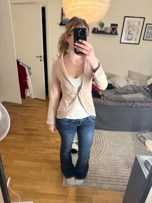 kofta House of Lola - Säljer en otroligt fin och unik kofta/kavaj från populära House of Lola. Färgen är en mjuk beige/puderrosa nyans som passar till allt. Plagget ar gjort i ett mjukt och stretchigt trikåmaterial som gör den lika bekväm som en luvtröja, men spetsdetaljerna och kragen ger den en klädd och romantisk look.