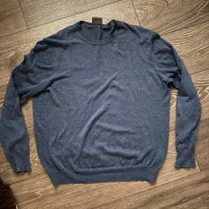 Mörkblå tröja från Oscar Jacobson - Klassisk mörkblå tröja från Oscar Jacobson i mjuk ullmix. Tröjan har rund halsringning, ribbade muddar och lång ärm. Perfekt för lager på lager under kyliga dagar. Fri frakt