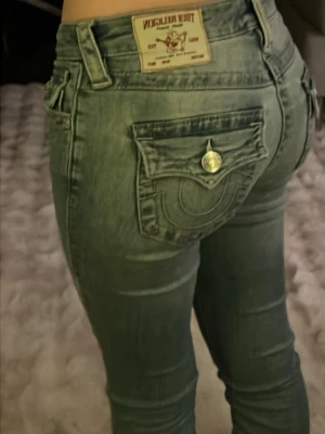 Ljusblåa True religion jeans - Väldigt sköna och väldigt snygga blåa true religion jeans, modellen är becca mid rise bootcut i storlek 24 men jag tycker att de är mellan 24 och 25 samt att de är lutar lite mot low rise så en lagom rise. Passar till allting och har fina detaljer bak. De har inget trasigt och alla detaljer är som om de var nya. Väldigt lätt stylat och jag gillar verkligen de. Jag säljer dessa eftersom jag är pank och då de är lite för korta för min stil.