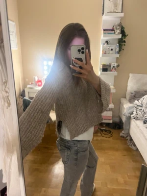 Beige stickad croppad tröja Gina Tricot - Supermysig beige stickad tröja från Gina Tricot. Modellen är croppad med breda, långa ärmar och grov ribbstickning. Perfekt att slänga på sig över ett linne eller t-shirt för en chill look.