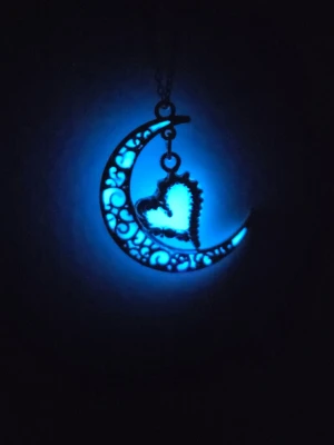 Glow in the dark halsband – Måne & Hjärta 🌙💙 Handgjort - Ett magiskt halsband med en detaljerad halvmåne och ett hjärta i silverton! Jag har fyllt mönstret för hand med ett speciellt material av högsta kvalitet. ​✨ I ljuset: Stilren vit finish. 🌙 I mörkret: Lyser upp i en fantastisk blå färg (laddas enkelt med UV-ljus eller solljus). ​Materialet är giftfritt och lyser starkt i många timmar. Kedjan är i hållbart rostfritt stål (45 cm). Helt nytt och unikt!