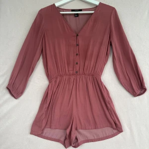Långärmad brun/gammalrosa playsuit i S. Forever-21 - •Brun / rostbrun långärmad playsuit med v-ringning och knappar framtill i S. från Forever 21.  •Playsuiten har resår i midjan, fickor på sidorna och mjukt, lätt tyg.  •Playsuit är i S men användes då jag hade XXS, så den skulle nog passa mellan S-XXS. •Använd men fortfarande mycket fräsch. 