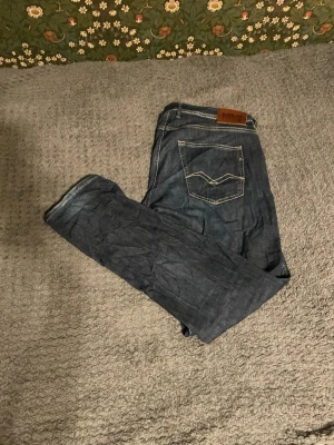 Replay mörkblå jeans straight fit - Säljer ett par mörkblå jeans från Replay med klassisk femficksdesign och snygga kontrastsömmar på bakfickan. Jeansen har slim passform och normal midja, tillverkade i stretchigt denim material. Perfekt för dig som gillar stilrena och tidlösa jeans. W34 L32